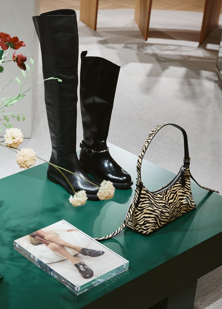 A table displays a Zebra print bag and two pairs of boots at a Vagabond pop-up store in Galeries Lafayette