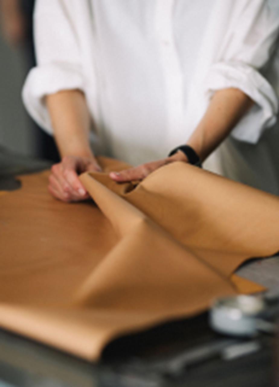 Hands gently folding and examining a piece of light-colored leather