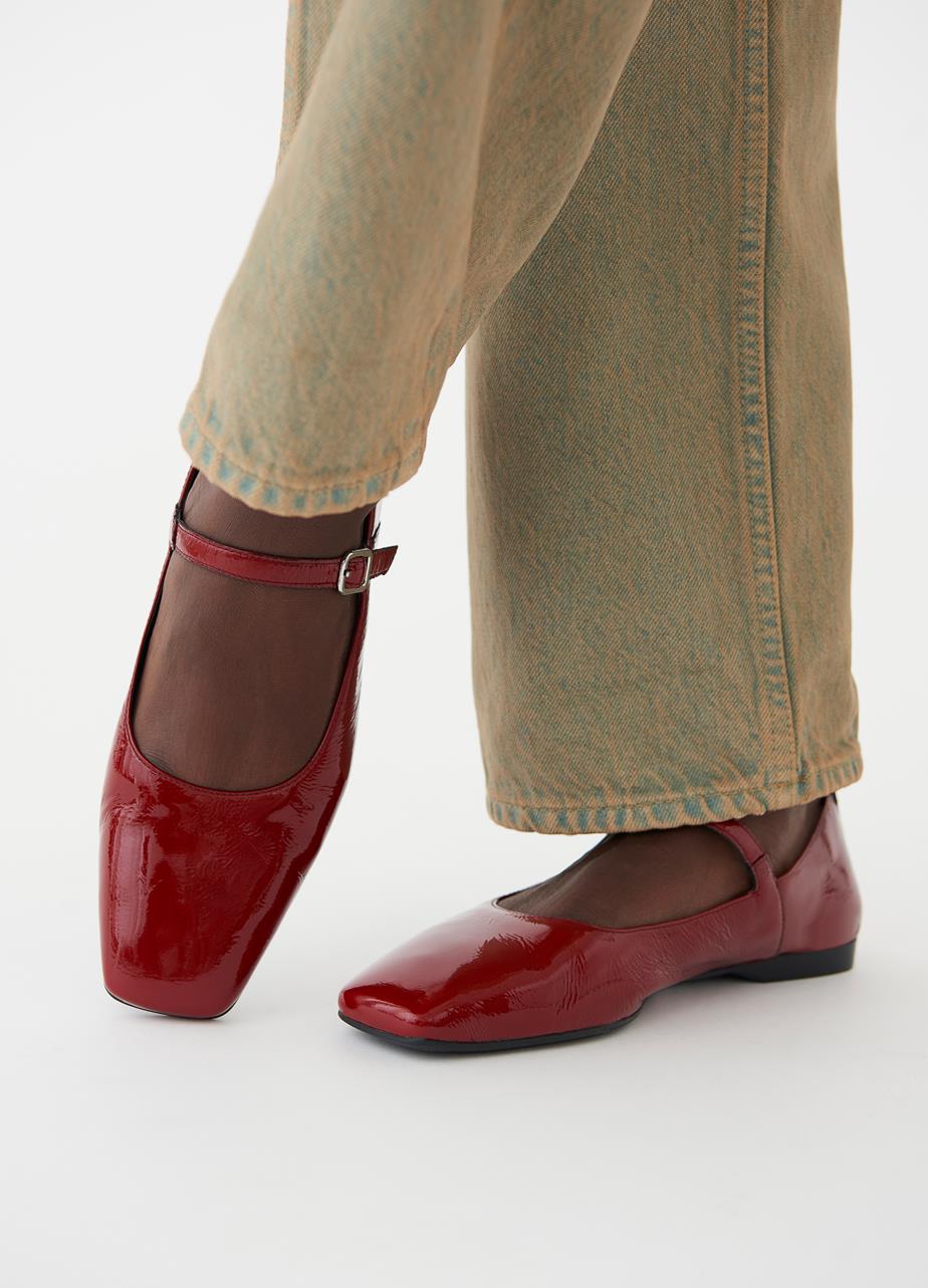 Red Delia Mary Jane flats in patent leather with square toes, styled with beige jeans.