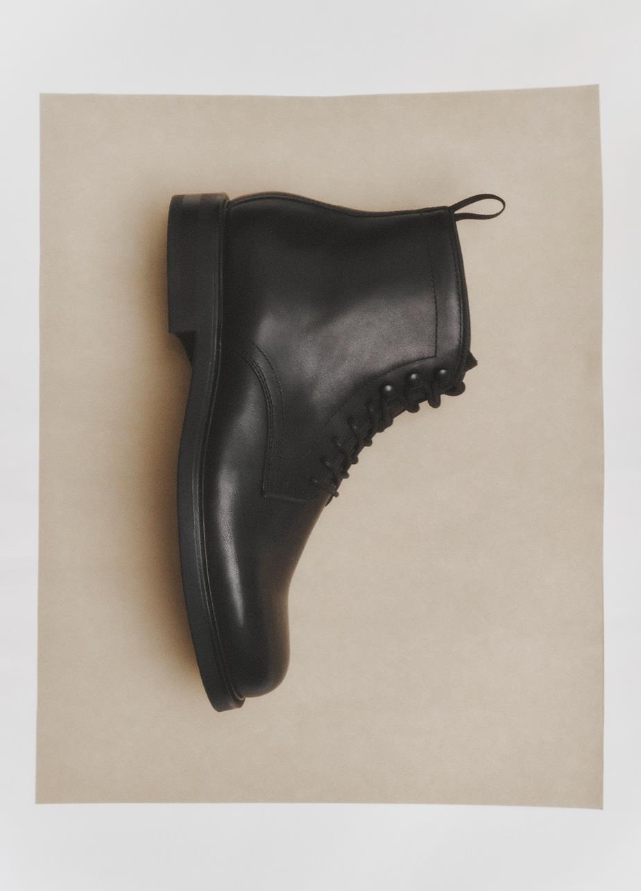 Black leather lace-up Floyd Boot viewed from above on a beige background