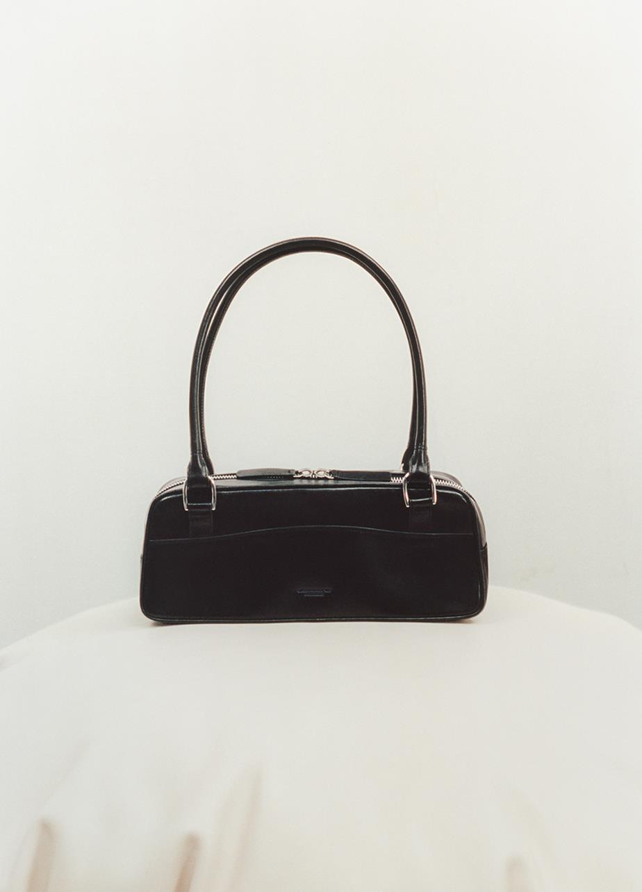 The black leather Nomi Mini Bag displayed on a white surface