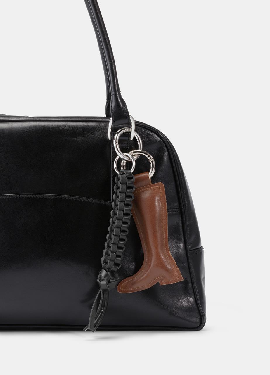 Black handbag with a brown leather boot charm and black braided charm.