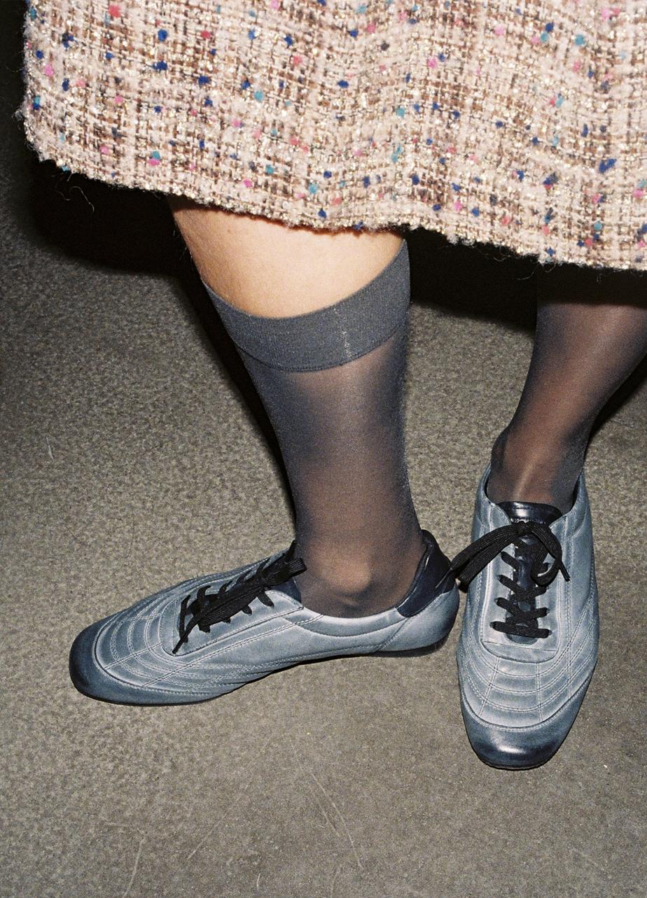 Close-up of Hillary Soccer sneakers in washed black, styled with sheer socks.