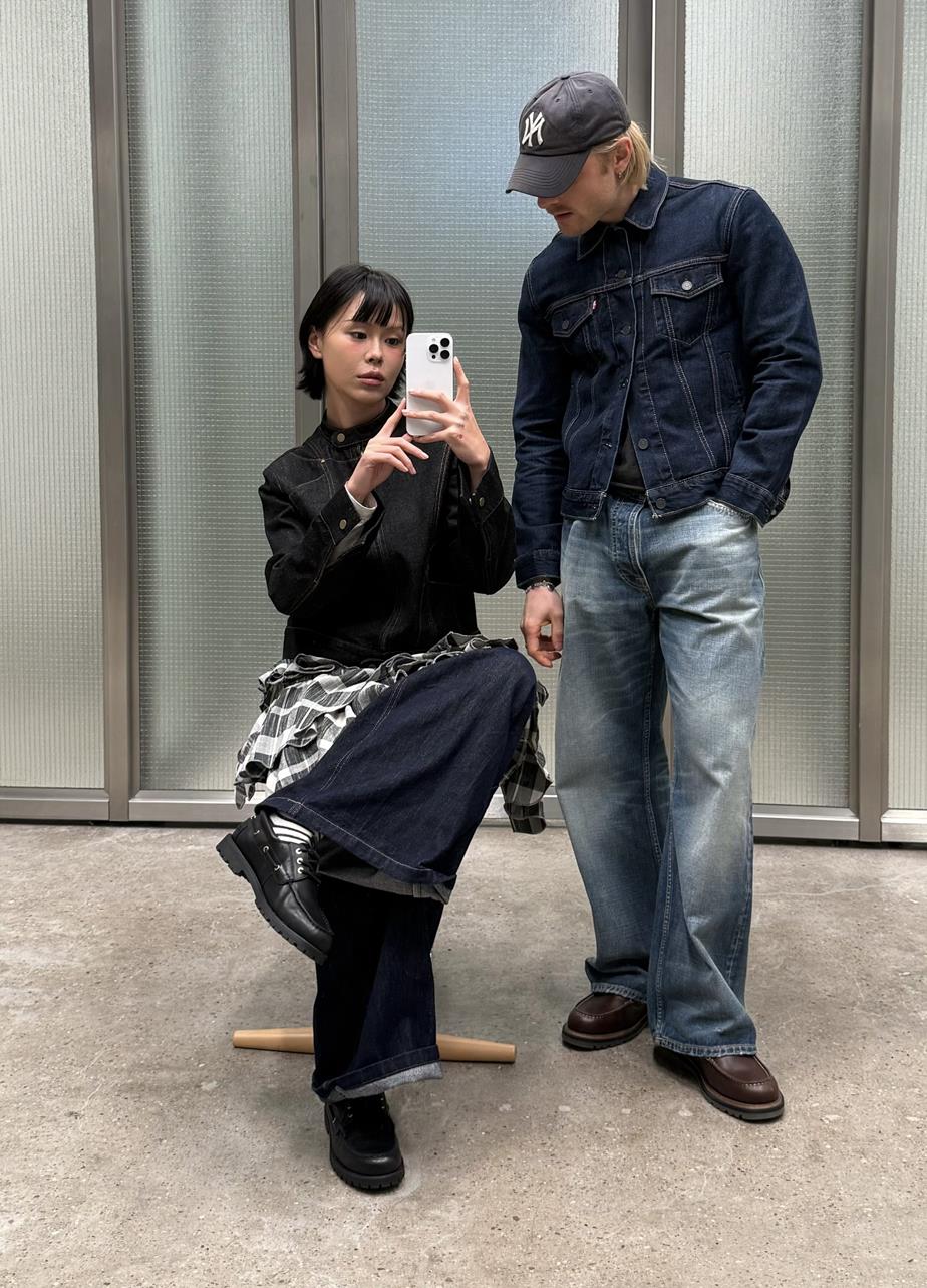 Two individuals in denim wearing boat shoes in an industrial indoor setting.