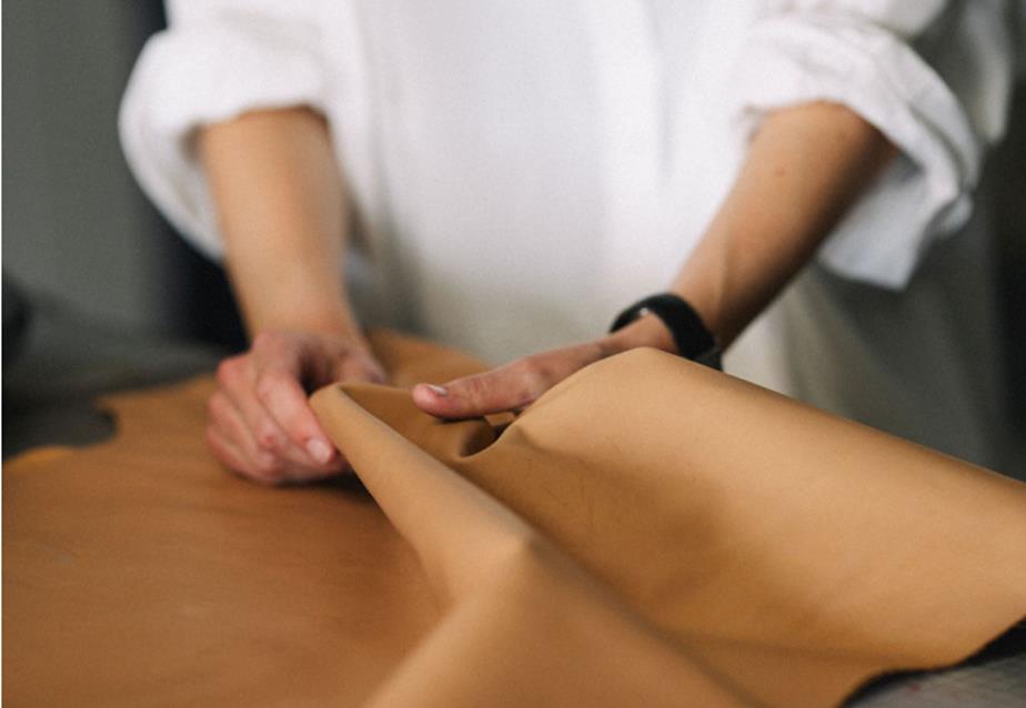 Hands gently folding and examining a piece of light-colored leather