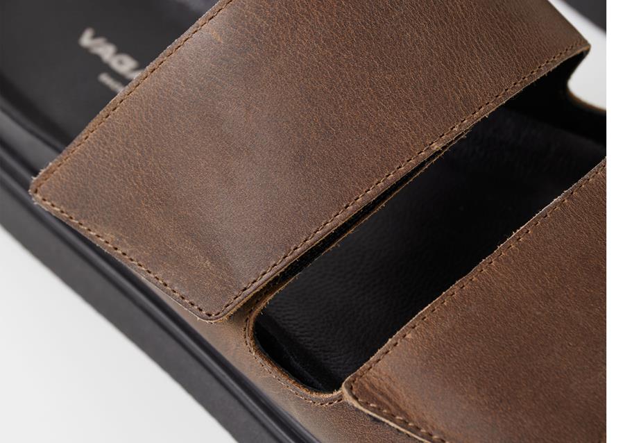 Close-up of brown sandals, designed with black outsole and adjustable velcro straps.