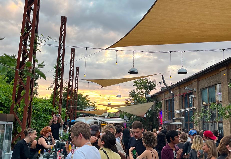 A diverse crowd enjoying the Vagabond open air event in Berlin, surrounded by colorful decorations and lively atmosphere