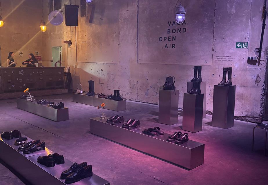A room in a warehouse with dimed lighting and purple spotlights featuring an array of shoes on display