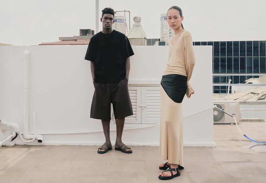 Two people standing on a rooftop, overlooking the city skyline in the background.