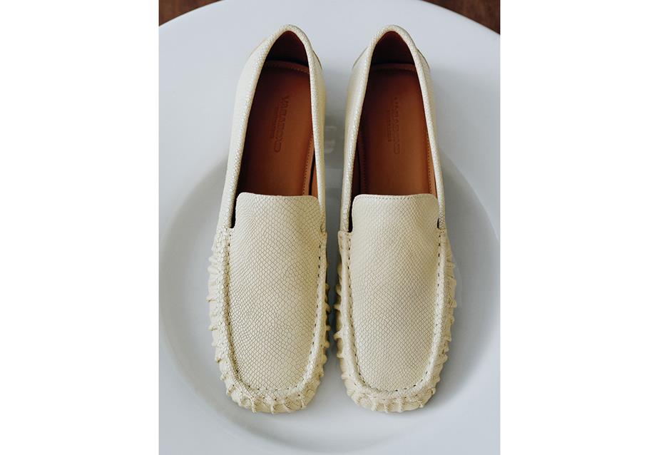 A pair of white Mika loafers placed on a white plate.