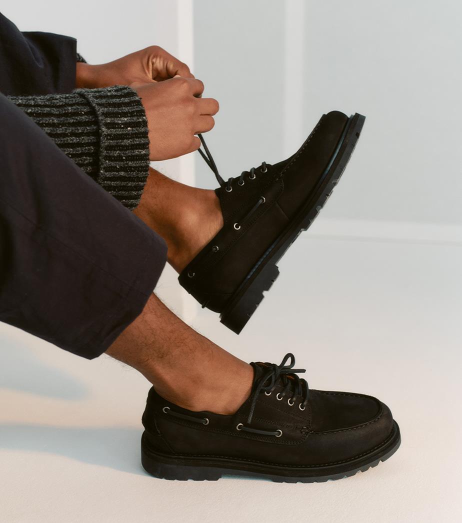 Black boat shoes being tied in a clean, modern setting.