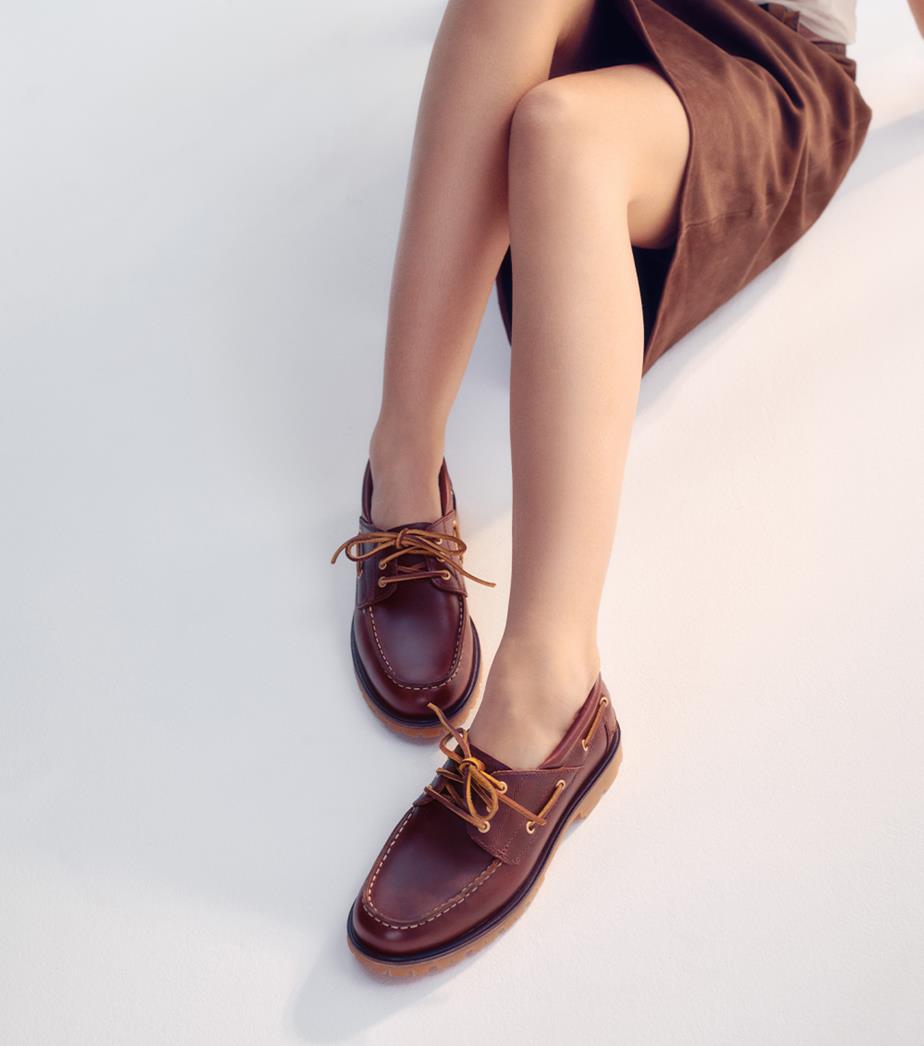 Brown boat shoes styled with a skirt for a relaxed yet polished look.