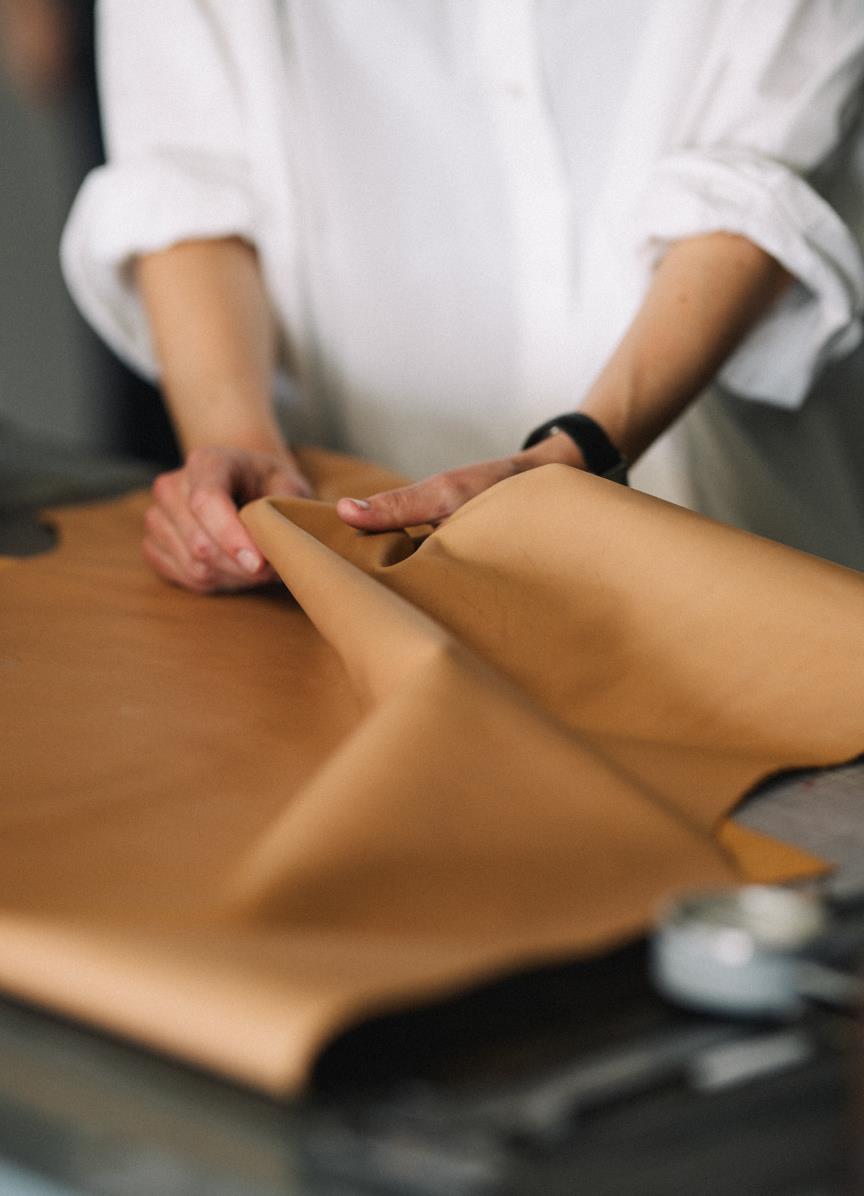 Hands gently folding and examining a piece of light-colored leather