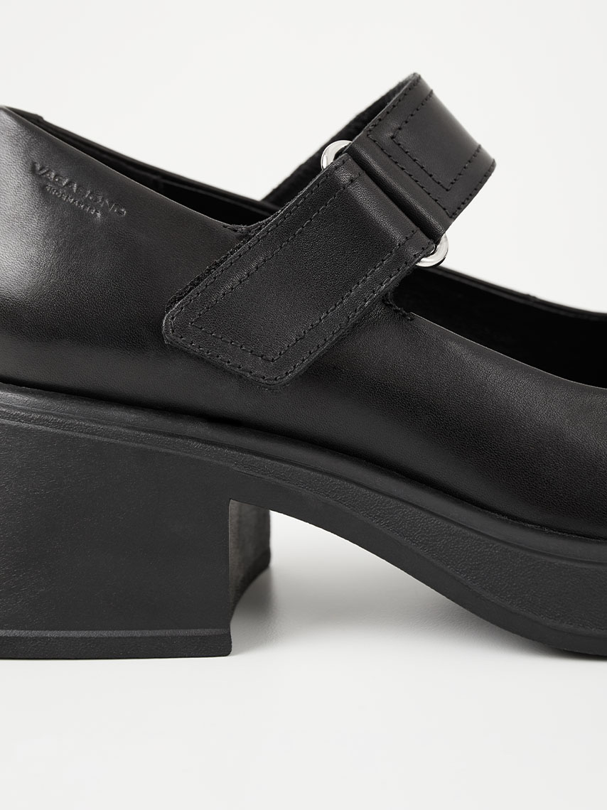 Chunky topánky Mary Jane Cosmo 2.0 z čiernej kože v kombinácii s rebrovanými bielymi ponožkami a čiernymi nohavicami.
