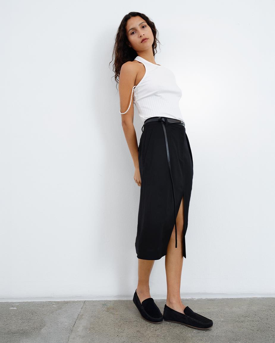 A woman wearing a white tank top, a black skirt and a pair of black Larissa Loafers